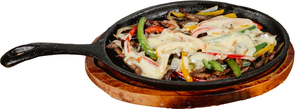 Alambre de borrego con tocino, chile morrón y queso gratinado en sartén de hierro sobre tabla de madera